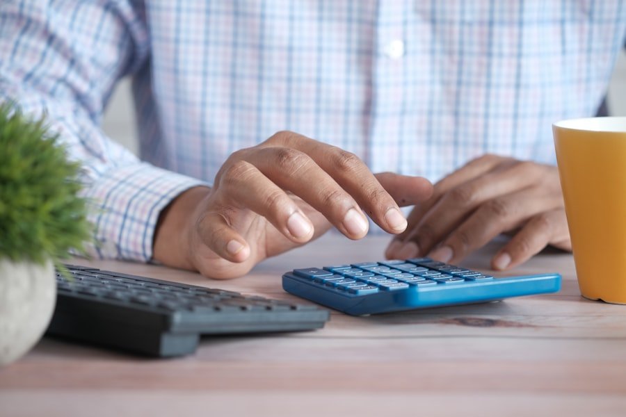 Person using a calculator with a coffee mug